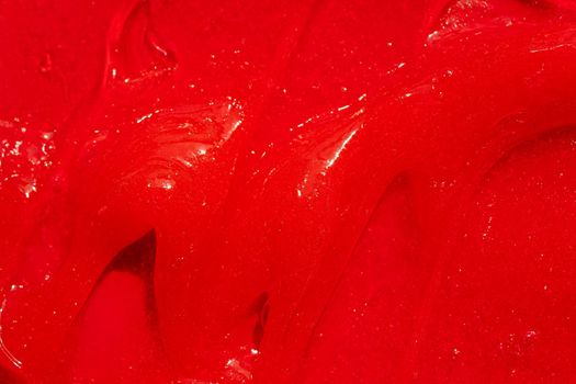 Red gel texture. Cosmetic clear liquid cream smudge. Skin care product sample closeup. Toothpaste or wax background