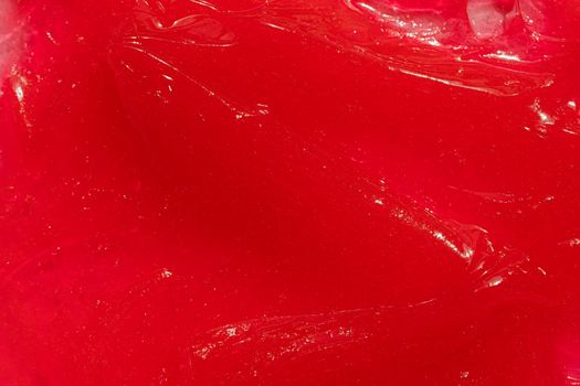 Red gel texture. Cosmetic clear liquid cream smudge. Skin care product sample closeup. Toothpaste or wax background