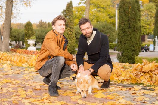 Father and son with a pet on a walk in the autumn park.