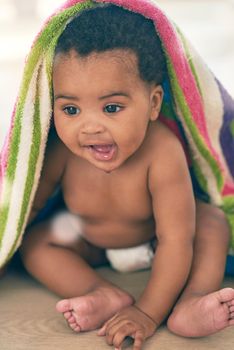 Sweet bundle of joy. an adorable baby girl covered in a colorful blanket at home