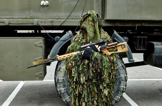 Close-up portrait of a military sniper in camouflage green army clothes with a Degtyarev sniper rifle in his hand. Armament of the Russian and Belarusian armies.