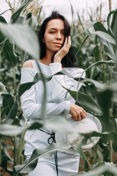 A brunette girl in a white dress in a cornfield. The concept of harvesting.