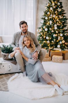 A happy couple in love - a man and a woman. A family in a bright New Year's interior with a Christmas tree.