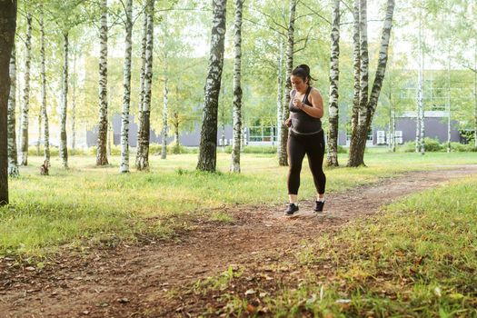 A charming brunette woman plus-size body positive practices sports in nature.