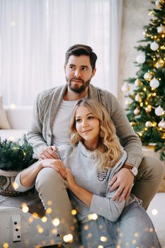 A happy couple in love - a man and a woman. A family in a bright New Year's interior with a Christmas tree.