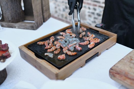 The chef prepares shrimp on the plancha
