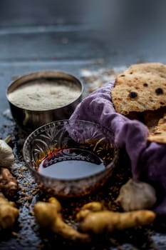 Shot of Gujarati breakfast consisting of round bread bhakri and lasun chutney. Shot of bhakhri, with wheat flour, garlic chutney, salt, ginger, and some whole wheat grains on a black glossy surface.