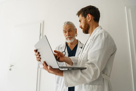 Two doctors are looking at something on the laptop in the doctor's office. High quality photo