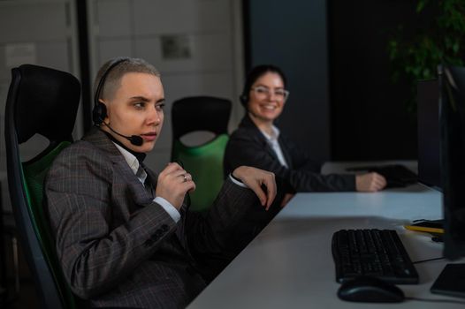 Two women in protective masks are bored at work. Call center operators at the desk.