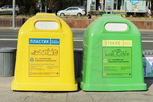 Moscow, Russia, 08 14 2022: Two containers for sorting waste, different in color. For plastic and glass. The concept of separating garbage for further processing.