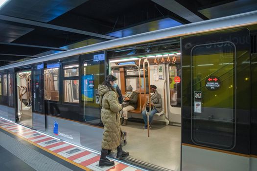 Brussels, Belgium - 01.31.2022 A young woman enters a subway car in a big city on a platform while masked people sit there. High quality photo