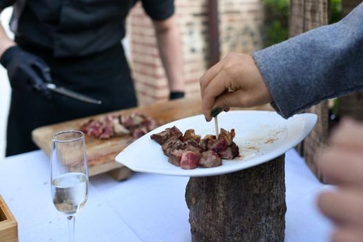 The chef cooks the veal at a plancha and the guest tastes the meat