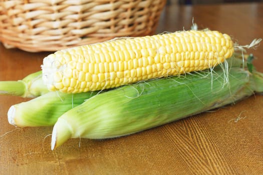 Raw cobs of young corn on a wooden table.