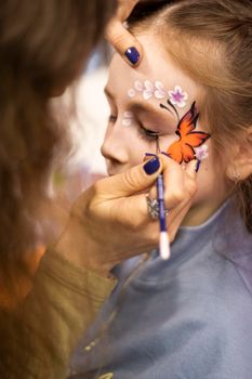 selective focus. A makeup artist works. childrens makeup face paint drawings Girls face painting. Little girl having face painted on birthday party. closed eyes. High quality photo