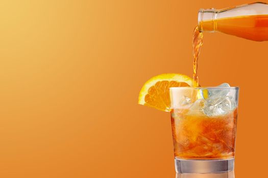 Glass of iced cold aperol spritz cocktail decorated with slices of orange. Aperitif, making coctail, pouring liquid into glass full of ice, isolated on orange background. Copy space