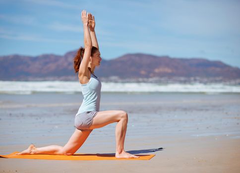 Keep calm and yoga on. a young woman practicing her yoga routine at the beach