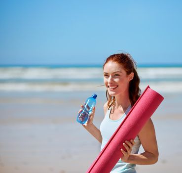 Yoga is always a good idea. a young woman posing with her yoga mat on the beach