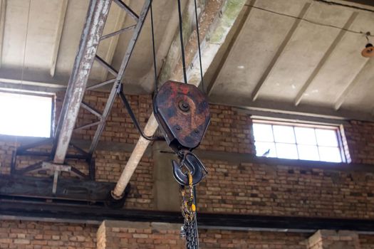 Large rusty hook under the ceiling in an old building close up