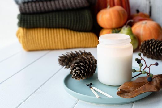 Hello fall. Cozy warm image. High angle view autumn composition with sweaters and candles, white candle mockup design