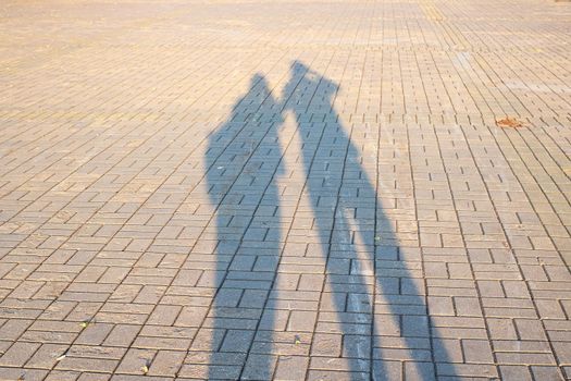 Two shadows of people on the sidewalk close up