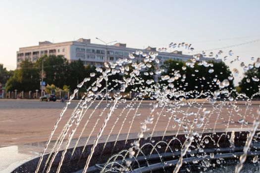 Splashes of water in the fountain at sunset close up