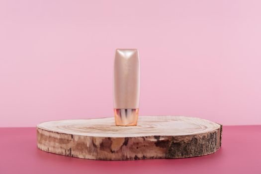 Cosmetic liquid foundation nude cream cosmetics bottle mockup on wooden podium. Beige packaging concealer base product mock up on pink background. Skincare beauty primer, bb corrector