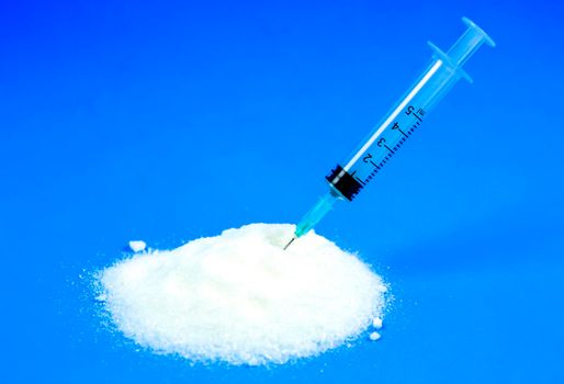 Conceptual photo of syringe and sugar emulating sugar addiction