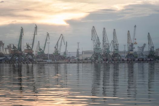 In the evening, the silhouette of port cranes. Ready to load containers from cargo ships.