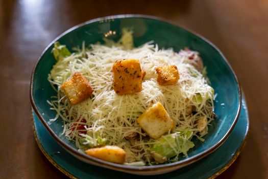 delicious meat beautifully decorated Caesar salad with grated cheese, croutons in a beautiful plate. culinary delights. Close-up, selective focusing