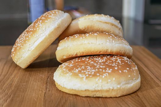frozen buns for a burger lie in a stack on a wooden cutting board, the process of preparing a burger in the kitchen at home