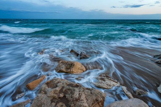 long exposure seascape with waves flowing between rocks at sunset