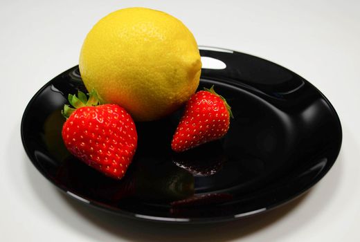 strawberries and lemon in a black plate