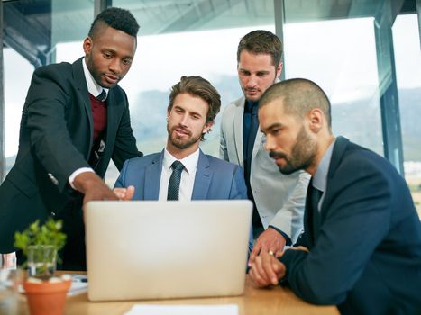 His ideas are game changing. a team of colleagues having a meeting around a laptop in a modern office