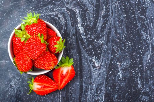 Strawberries on black marble. Ripe strawberries in a saucer on a black background. Place to insert text.