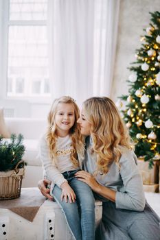 Happy family: mother and daughter. Family in a bright New Year's interior with a Christmas tree.