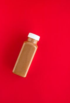 Detox, diet and healthy lifestyle concept - Chocolate banana smoothie bottle on red, flatlay