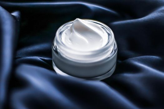 Beauty, anti-age cosmetics and skincare concept - Luxury face cream jar on a dark blue silk