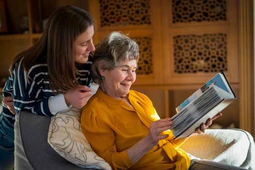 Grandmother and her young granddaughter spent great time together, family members look at photos from the youth of an elderly parent, through the pages of the album and recall funny stories from life.