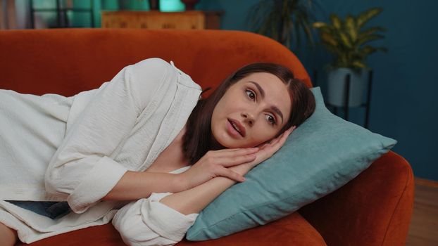 Scared tired caucasian adult girl wakes up from nightmare in bedroom at home. Poor bad sleep of young woman stress, nervousness and anxiety, mental health. Loneliness, sickness, headache concept