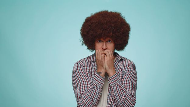 Panic attack. Upset scared frightened bearded adult man biting nails, feeling worried nervous about serious troubles, stress and anxiety disorder, guilty. Young one guy on blue studio wall background
