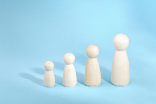 Wooden figurines standing in a row from low to high. Person growth on blue background. Management strategy. Leadership concept. Teamwork idea.
