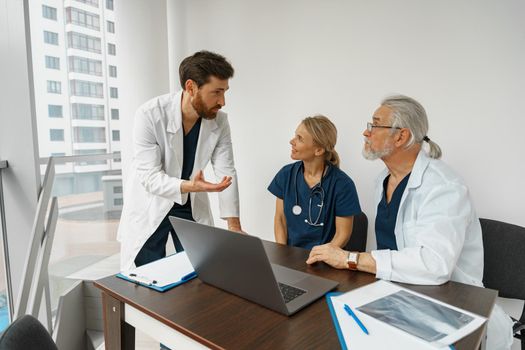 Group of doctors sitting at meeting table in conference room during seminar. High quality photo