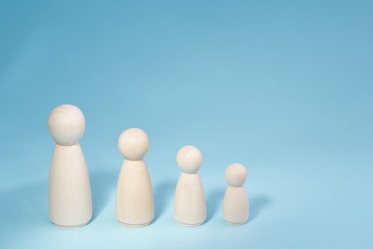 Wooden figurines standing in a row from high to low. Concept person growth on blue background. Management strategy. Leadership concept. Teamwork idea.