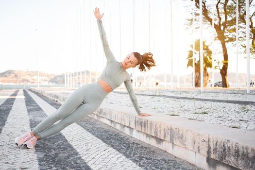 Full length, strong fit girl sportswear training side plank outdoor summer day, doing perfect plank exercise and looking motivated, concentrated on pilates workout. Health care, sport activity