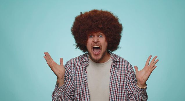 Bearded adult man scared fearful, covering ears with hands, closing eyes, meeting his own phobia, evidence horror event, screaming, shouting at loud, freaked out. Young guy alone on blue background