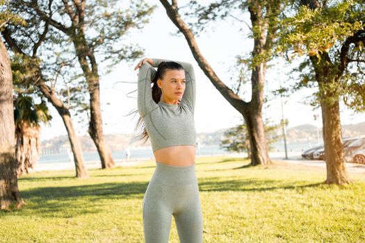 Woman Stretching And Warming-Up Before Running. Fit sport woman stretching her body warm up before workout outdoor. The girl in sportswear exercises outside in summer park for health and wellbeing.