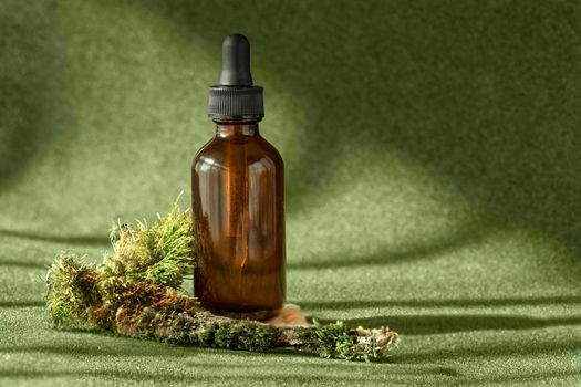 Amber glass bottle with serum, essential oil, anti aging collagen cosmetic beauty product among the green mossy backdrop. Natural organic cosmetic, eco or bio concept, biophilia design