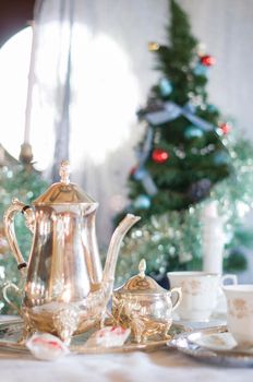 English tea party, silver tea set against the background of the Christmas tree tinsel. High quality photo