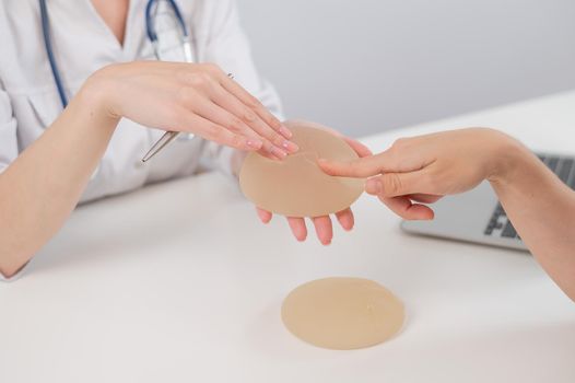 Caucasian woman and plastic surgeon choosing breast implants