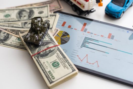 a toy tank, dollars and a tablet.